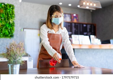 New Normal Startup Small Business Portrait Of Asian Womanwearing Protection Mask And Face Shield Cleaning Table In Coffee Shop While Social Distancing