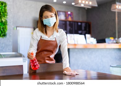 New Normal Startup Small Business Portrait Of Asian Woman Barista Wearing Protection Mask And Face Shield Cleaning Table In Coffee Shop While Social Distancing