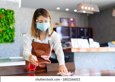 New Normal Startup Small Business Portrait Of Asian Woman Barista Wearing Protection Mask And Face Shield Cleaning Table In Coffee Shop While Social Distancing