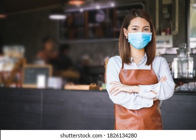 New normal startup small business Portrait of Asian woman barista wearing face mask working in coffee shop while social distancing