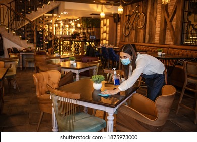 New Normal Startup Small Business Portrait Of  Woman Barista Wearing Protection Mask Cleaning Table In Coffee Shop While Social Distancing. New Normal Hygiene Restaurant Concept.