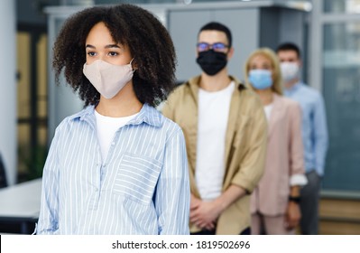 New Normal And Temperature Check Before Work. Millennial Multiracial Employees In Protective Masks Stand In Line With Social Distancing At Office In Morning, Free Space, Blurred, Indoors