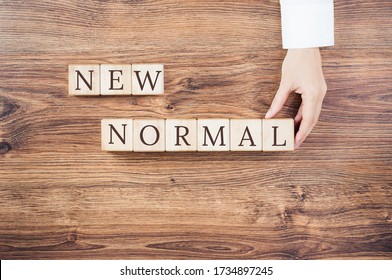 New Normal Text On Building Blocks With A Hand In White Office Shirt Or Doctor. Adapting To New Life Or Business Post-lockdown After COVID Pandemic. Business With Social Distancing Personal Hygiene