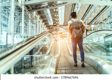 New Normal And Travel Insurance Concept.Young Caucasian Man Wearing Face Mask And Carrying Backpack On Escalator Or Travelator Walkway In Airport Terminal,protection During Coronavirus Pandemic.