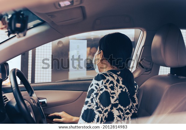 New normal woman in protective mask ordering\
food and drinks in drive through\
cafe