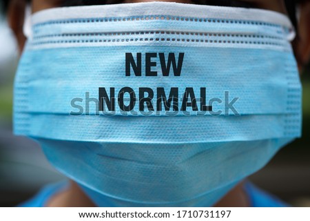 NEW NORMAL word on 3 ply face surgical mask. Life after pandemic concept.