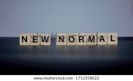 NEW NORMAL word on wooden alphabet cube. New normal after covid-19 pandemic with social distancing, good hygiene.