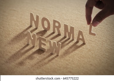 NEW NORMALwood word on compressed or corkboard with human's finger at L letter. - Shutterstock ID 645775222