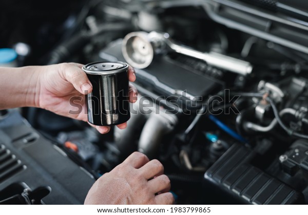 New Oil filter in\
hand a man and wrench in the gasoline engine compartment : service\
concept of car