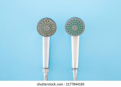 New and old shower heads on light blue table background. Pastel color. Compare two objects with and without limescale. Dirty and clean. Closeup.