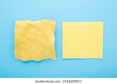 New and old yellow cleaning sponge rags on light blue table background. Pastel color. Compare two objects. Closeup. Top view. - Powered by Shutterstock