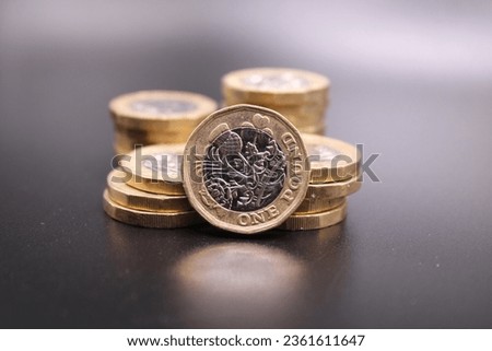 New one pound coins on a dark background.  Piles of coins and one standing in front.  British coin.  British pound. Dark background.  Black background