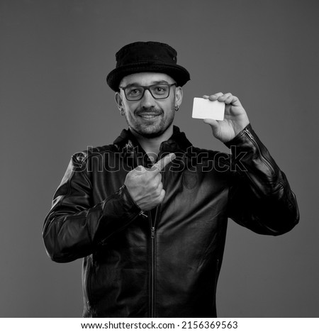 New opportunities. Smiling trendy man holding credit card and pointing at it with his forefinger while being ready for opening his business