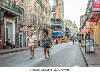 New Orleans, LA - October 25, 2021: Friends Walk Along Bourbon Street In The French Quarter, At Sunset, With The City Skyline Beyond.