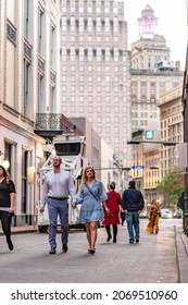 New Orleans, LA - October 28, 2021: A Beautiful Couple Explores Bourbon Street In The French Quarter With The Downtown City Skyline Beyond.