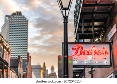 New Orleans, LA - October 28, 2021: A Neon Sign On Bourbon Street With The City Skyline And Sunset Beyond, In The French Quarter.