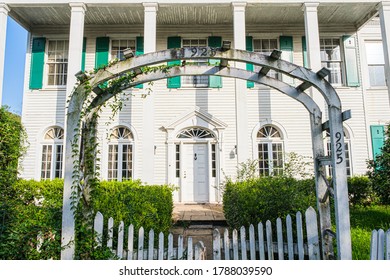 NEW ORLEANS, LA, USA - JULY 30, 2020: Old Large White House In Uptown Neighborhood With Arbor, Trellis And White Picket Gate