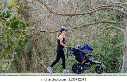 NEW ORLEANS, LA, USA - MARCH 5, 2022: Woman pushing her child in a stroller in Audubon Park