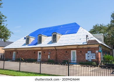 NEW ORLEANS, LA, USA - SEPTEMBER 9, 2021: Building with Hurricane Ida Damaged Roof Covered with Blue Tarp and Plastic