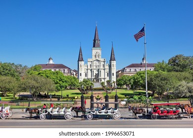 NEW ORLEANS, LOUISIANA, USA - JUNE 17,2021: Tourists mingle in Jackson Square, New Orleans, St. Louis Cathedral visible; horse and carriages wait to take people on tours of New Orleans in JUNE 2021.