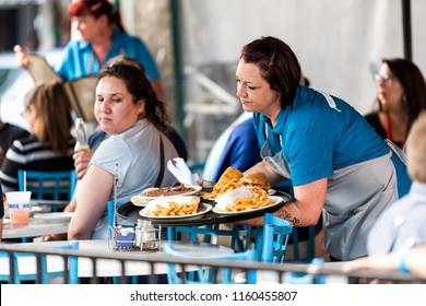 New Orleans, USA - April 22, 2018: Woman, Female Waitress Serving Cajun Creole Cuisine Food, Fries, Soup At The Market Cafe Restaurant, People Sitting At Table, Funny Looking Customer