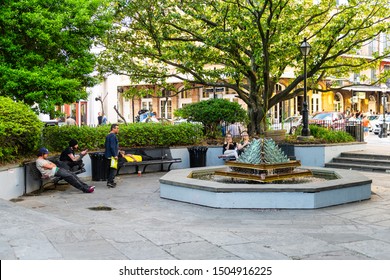 New Orleans, USA - April 22, 2018: People Sitting On Benches At LaTrobe Green City Park With Water Fountain In Louisiana Old Town