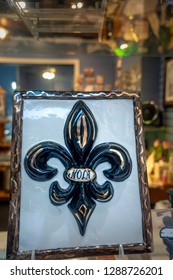 New Orleans, USA - Dec 4, 2017: Handmade, hand-painted framed symbol of the State of Louisiana - the Fleur de Lis, as displayed at an outside window of a souvenir shop.