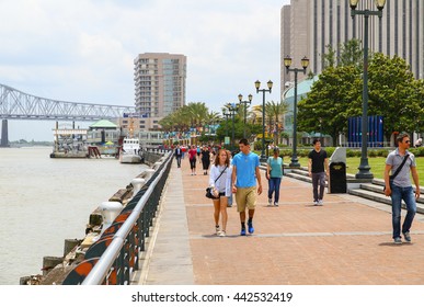 NEW ORLEANS, USA - MAY 14, 2015: Pedestrians on the New Orleans Riverwalk with the Mississippi River to the left and the Crescent City Connection and highrises in the back. 