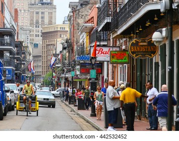 NEW ORLEANS, USA - MAY 14, 2015: Bourbon Street in French Quarter with many pedestrians and vehicles. There are a lot bars with neon signs, in the back modern highrises.
