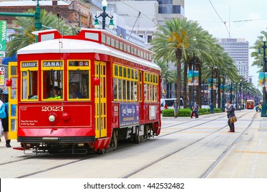 NEW ORLEANS, USA - MAY 14, 2015: Red Streetcar On Canal Street, In The Back Another Streetcar Approaching And People Crossing The Street.