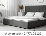 New orthopedic mattress with blanket on stylish bed in room