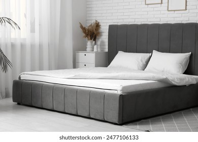 New orthopedic mattress with blanket on stylish bed in room