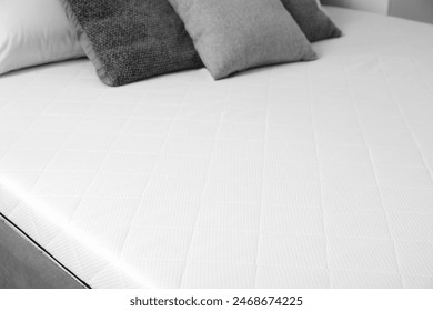 New orthopedic mattress on stylish bed in room, closeup