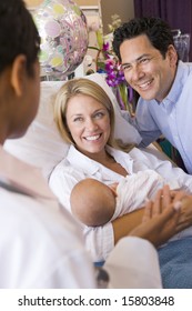 New Parents With Baby Talking To Doctor And Smiling