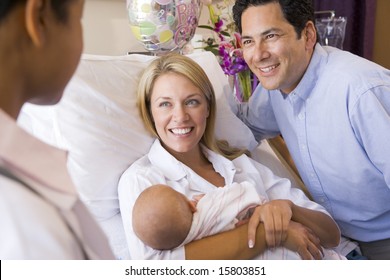 New Parents With Baby Talking To Doctor And Smiling