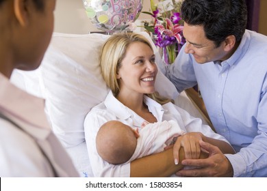 New Parents With Baby Talking To Doctor And Smiling