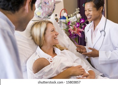 New Parents With Baby Talking To Doctor And Smiling