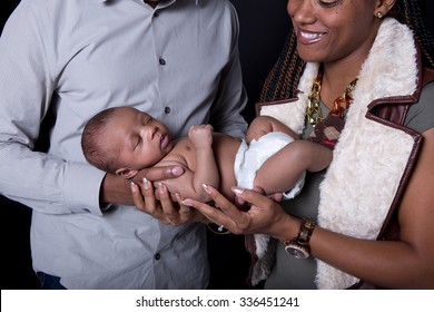 New Parents Looking At Their Newborn On A Black Background