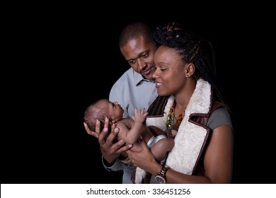 New Parents Looking At Their Newborn On A Black Background