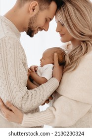 New Parents Smiling And Holding Their Newborn Baby Girl. 