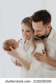 New Parents Smiling And Holding Their Newborn Baby Girl. 