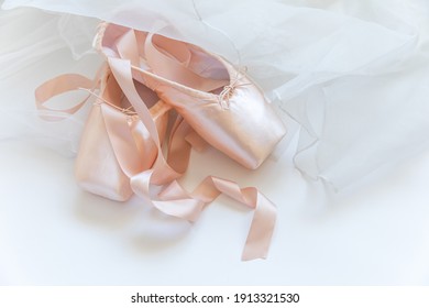 New pastel beige ballet shoes with satin ribbon and tutut skirt isolated on white background. Ballerina classical pointe shoes for dance training. Ballet school concept. Top view flat lay copy space