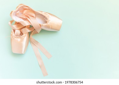New pastel beige ballet shoes with satin ribbon isolated on blue background. Ballerina classical pointe shoes for dance training. Ballet school concept. Top view flat lay copy space