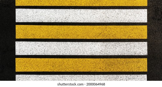 new pedestrian crossing with white and yellow lines on grey asphalt road in city centre on summer day upper view - Powered by Shutterstock