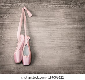 New pink ballet shoes hanging on wooden background.Vintage style.