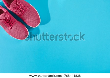New pink sneakers on blue background with copy space. Sport concept