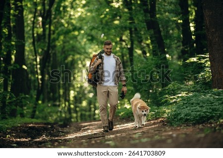 New places, exploring, walking, front view. Man tourist is with his dog in the forest.