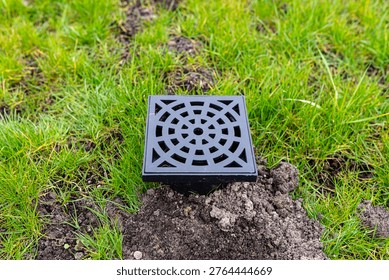 New plastic overflow pit with grid draining water in a garden