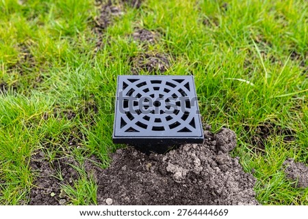 New plastic overflow pit with grid draining water in a garden