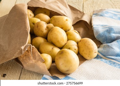 New potatoes on rustic table with brown paper bag